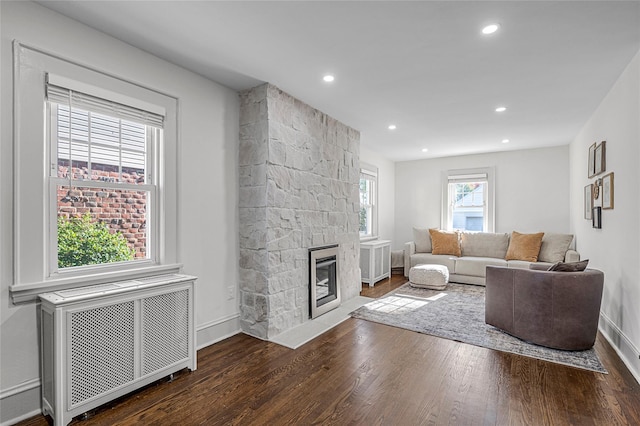 living room featuring dark hardwood / wood-style floors, radiator heating unit, and a fireplace