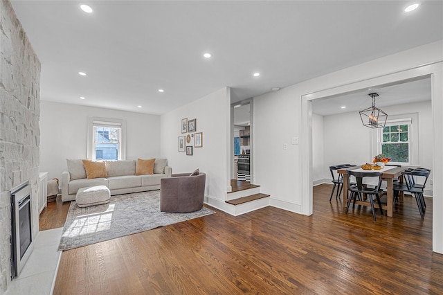 living room featuring a stone fireplace, a wealth of natural light, and dark hardwood / wood-style flooring