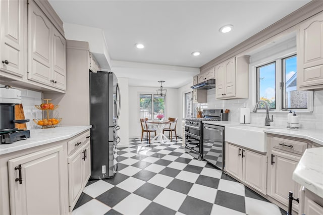 kitchen featuring sink, stainless steel appliances, tasteful backsplash, white cabinets, and decorative light fixtures