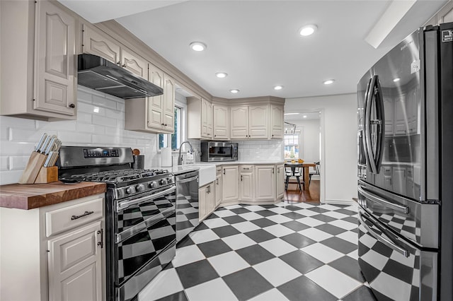 kitchen with stainless steel appliances, a healthy amount of sunlight, sink, and butcher block countertops