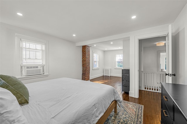 bedroom with cooling unit, radiator, and dark hardwood / wood-style flooring