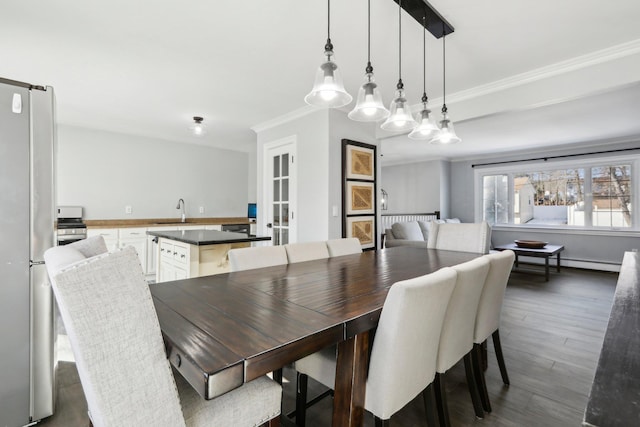 dining space with dark hardwood / wood-style flooring, sink, and ornamental molding