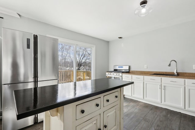 kitchen with appliances with stainless steel finishes, white cabinetry, sink, a breakfast bar area, and dark wood-type flooring