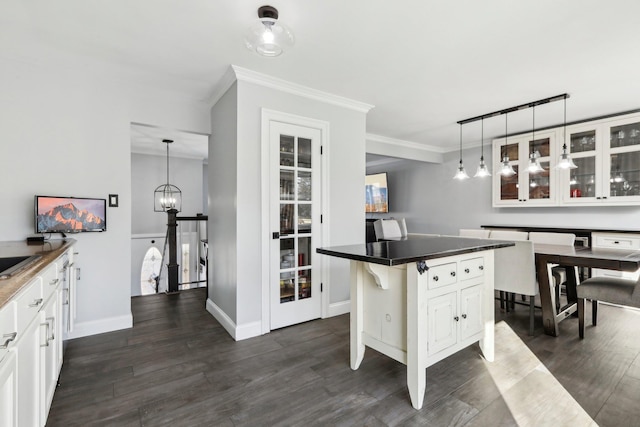 kitchen featuring hanging light fixtures, a center island, white cabinets, and a kitchen bar