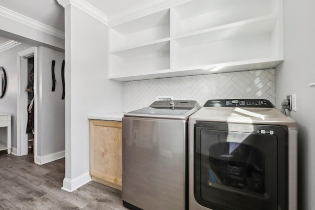 laundry room with crown molding, wood-type flooring, and washing machine and clothes dryer