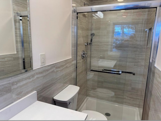 bathroom with tile walls, toilet, and a shower with shower door