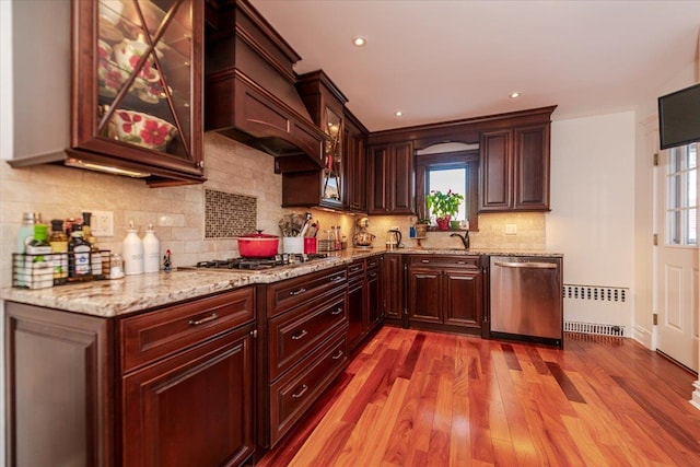 kitchen featuring radiator, sink, light hardwood / wood-style flooring, stainless steel appliances, and custom exhaust hood