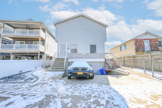 snow covered back of property featuring a garage