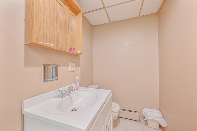 bathroom featuring vanity, baseboard heating, toilet, a drop ceiling, and tile patterned floors