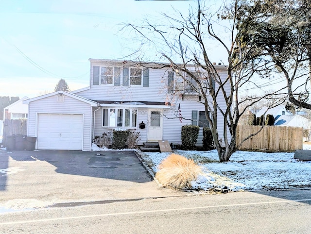 colonial-style house with an attached garage, driveway, fence, and entry steps