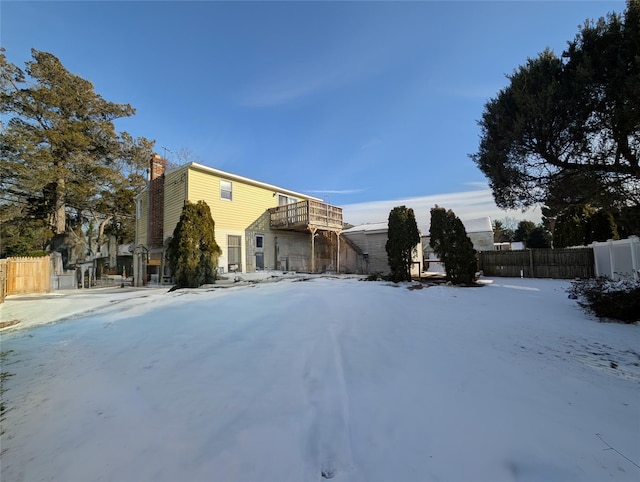 snow covered property featuring a chimney and fence