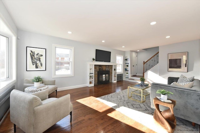 living room featuring dark wood-type flooring and a stone fireplace