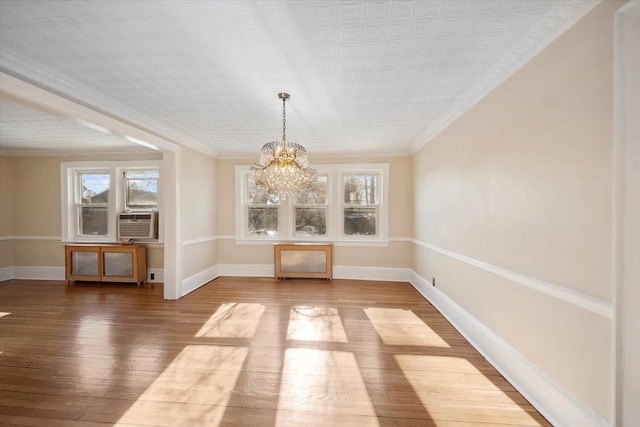 unfurnished dining area with cooling unit, a notable chandelier, wood-type flooring, and ornamental molding