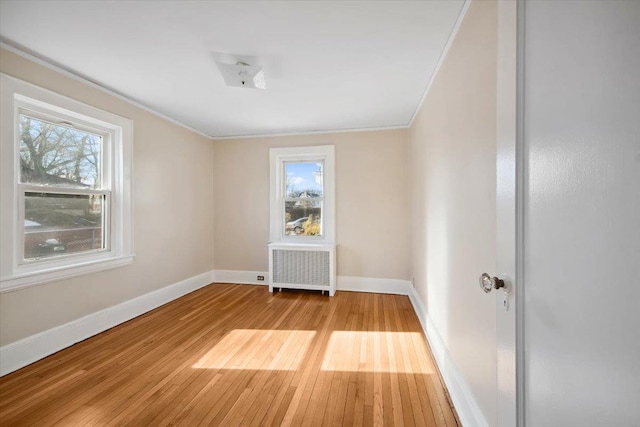 spare room featuring light hardwood / wood-style flooring, crown molding, and radiator heating unit