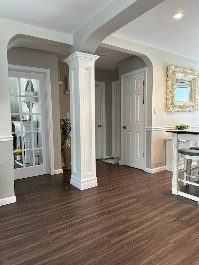 unfurnished dining area with ornate columns and dark hardwood / wood-style flooring