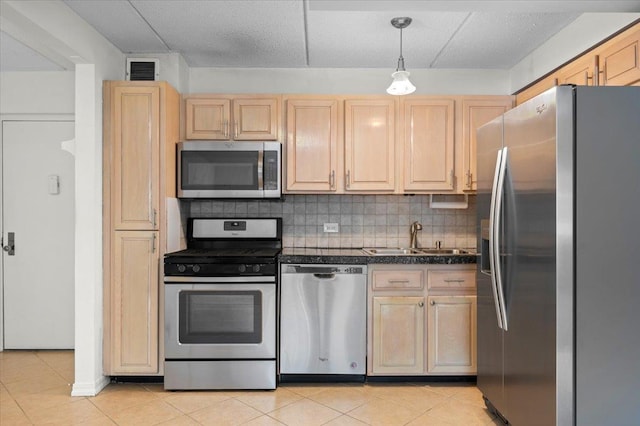 kitchen with appliances with stainless steel finishes, sink, pendant lighting, and light brown cabinetry