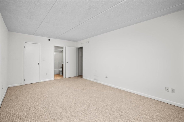 unfurnished bedroom with ensuite bathroom, carpet floors, and a textured ceiling