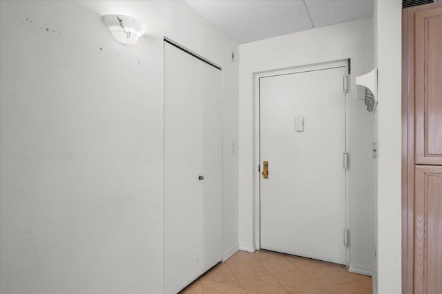 hall with a textured ceiling and light tile patterned floors