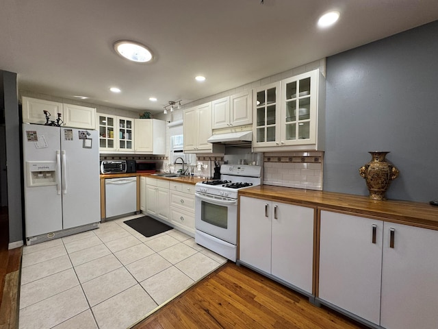 kitchen featuring white appliances, white cabinets, and wood counters