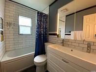 full bathroom with vanity, shower / bathtub combination with curtain, and toilet