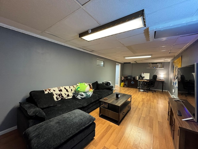 living room featuring a wall unit AC, light hardwood / wood-style floors, and a drop ceiling