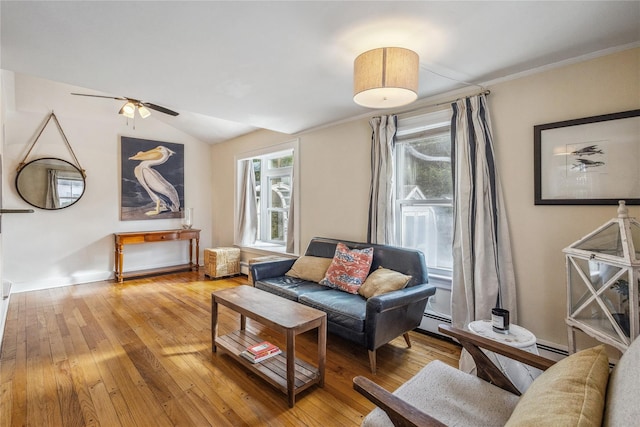 living room with lofted ceiling, light wood-type flooring, baseboard heating, ornamental molding, and ceiling fan