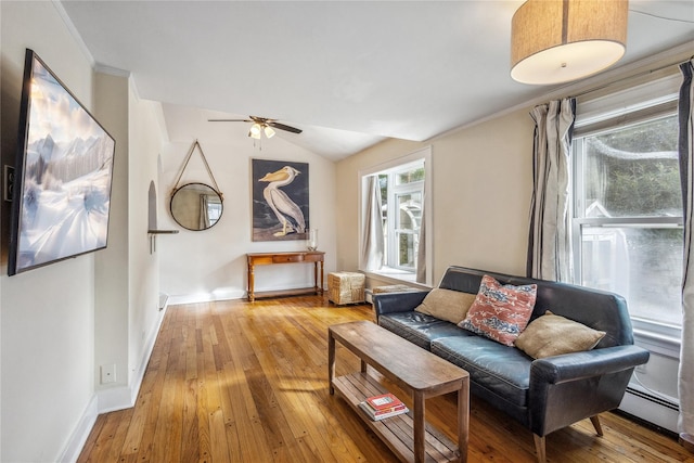 living room featuring vaulted ceiling, hardwood / wood-style floors, ornamental molding, ceiling fan, and baseboard heating