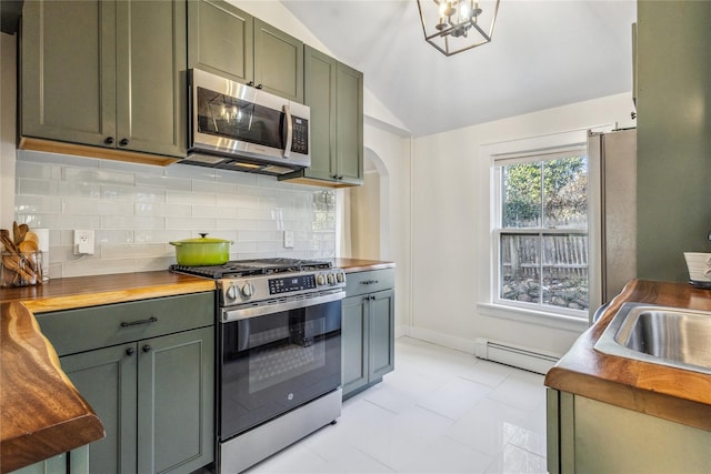 kitchen with lofted ceiling, butcher block counters, baseboard heating, green cabinetry, and stainless steel appliances