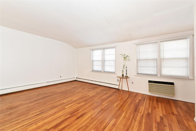 empty room featuring baseboard heating, vaulted ceiling, light hardwood / wood-style floors, and a wall unit AC