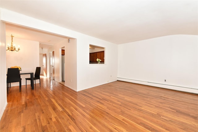 spare room with a chandelier, hardwood / wood-style floors, and a baseboard heating unit