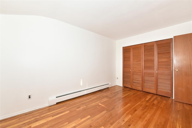 unfurnished bedroom featuring light hardwood / wood-style floors and a baseboard heating unit