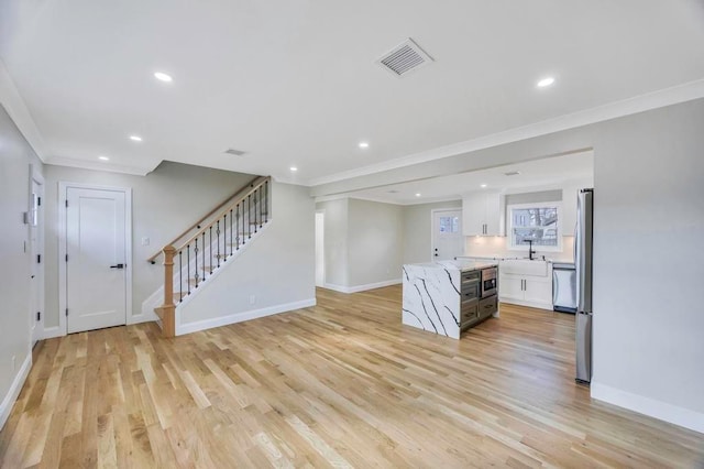 interior space with crown molding, sink, and light hardwood / wood-style flooring