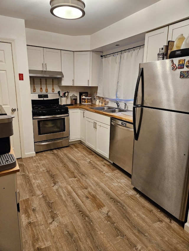 kitchen featuring appliances with stainless steel finishes, butcher block counters, light wood-type flooring, and white cabinets