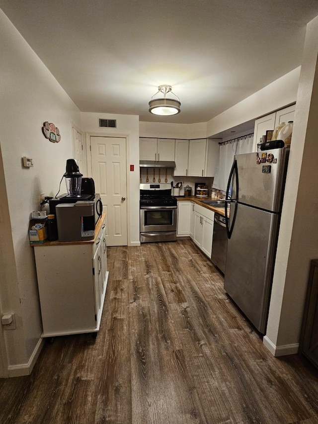 kitchen with appliances with stainless steel finishes, dark hardwood / wood-style flooring, sink, and white cabinets