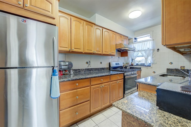 kitchen with appliances with stainless steel finishes, tasteful backsplash, sink, dark stone countertops, and light tile patterned floors