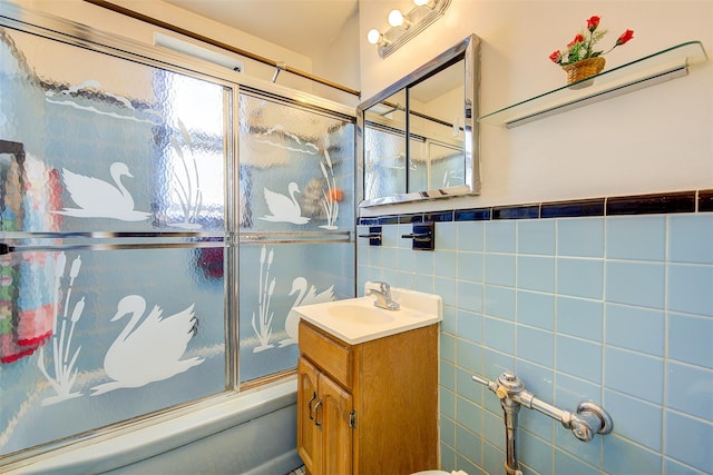 bathroom with enclosed tub / shower combo, vanity, and tile walls