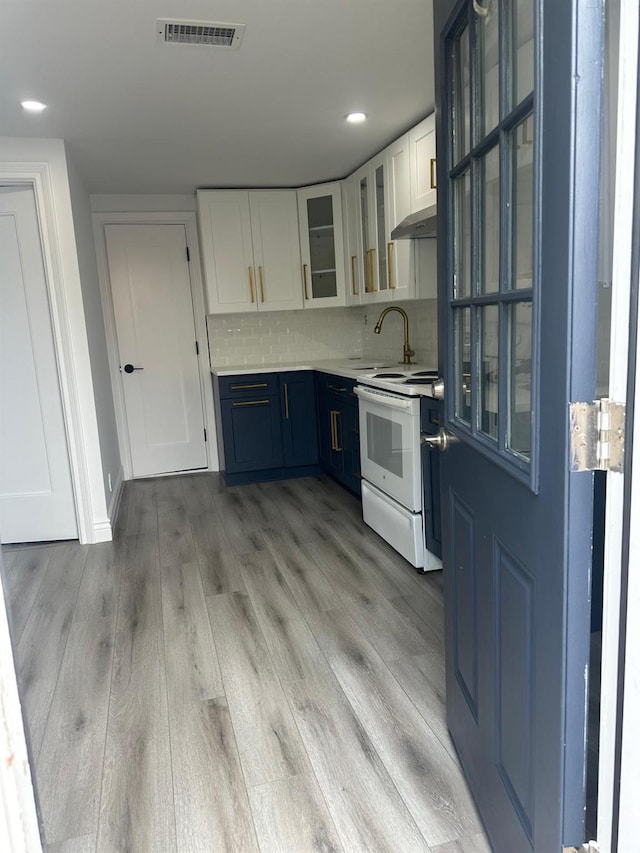 kitchen featuring white range with electric cooktop, light countertops, visible vents, glass insert cabinets, and white cabinets