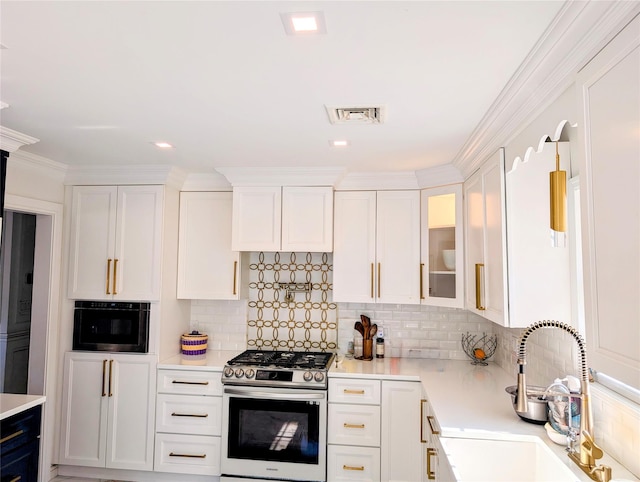 kitchen with glass insert cabinets, stainless steel range with gas cooktop, light countertops, and white cabinetry