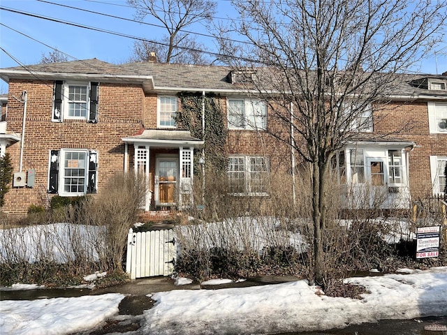 view of front facade featuring brick siding and fence