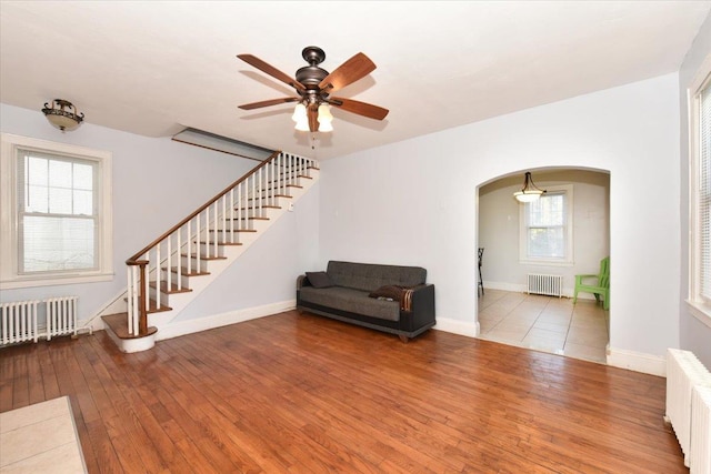 unfurnished living room featuring ceiling fan, radiator heating unit, and light hardwood / wood-style floors