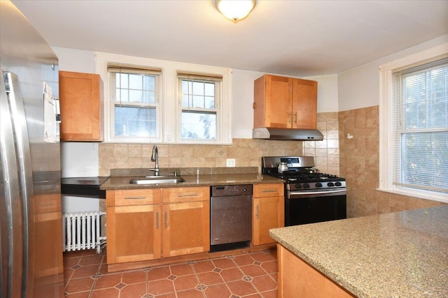 kitchen with radiator, sink, stainless steel appliances, a healthy amount of sunlight, and decorative backsplash