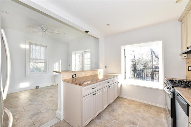 kitchen featuring ceiling fan, backsplash, stainless steel appliances, light stone countertops, and kitchen peninsula