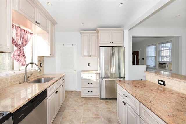 kitchen with light stone counters, appliances with stainless steel finishes, sink, and backsplash