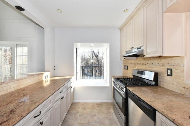 kitchen featuring light stone countertops, appliances with stainless steel finishes, a healthy amount of sunlight, and decorative backsplash