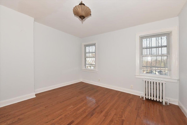 unfurnished room featuring dark hardwood / wood-style flooring and radiator heating unit