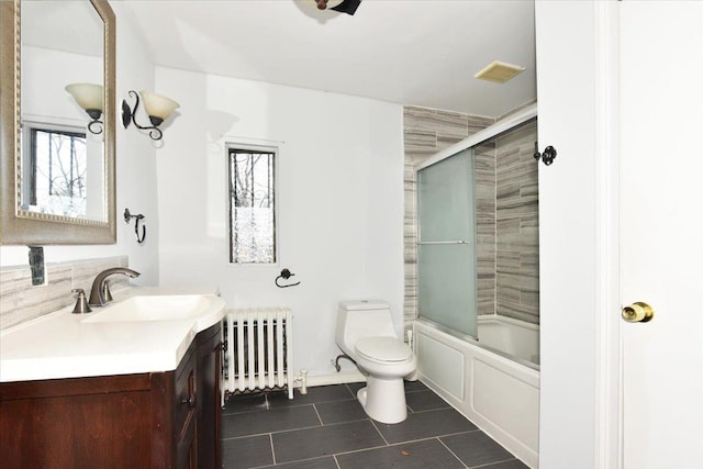 full bathroom with shower / bath combination with glass door, radiator heating unit, vanity, tile patterned floors, and toilet