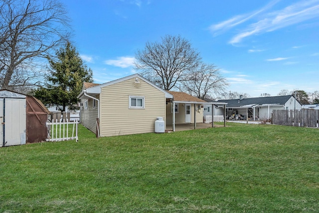 back of property with a yard, a patio area, and a storage unit