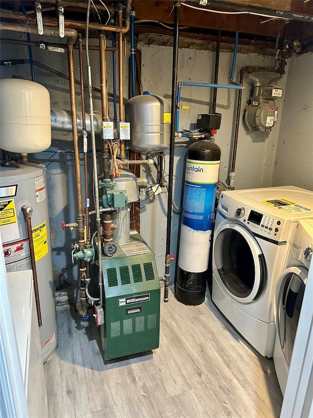 utility room with washing machine and clothes dryer, hardwood / wood-style floors, and water heater