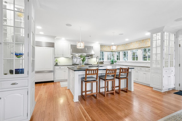 kitchen with wall chimney range hood, white cabinets, and a kitchen island