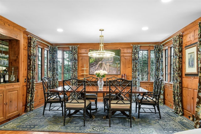 dining space with a chandelier and wood walls